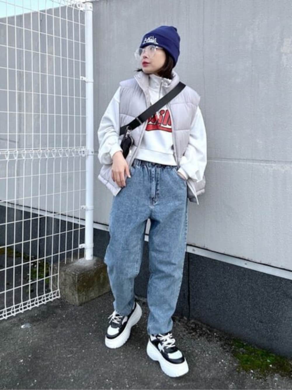 ホワイト系のスウェット、グレー系のダウンベスト、ブルー系のデニムパンツを着用したレディースの冬コーディネートの1枚目の写真