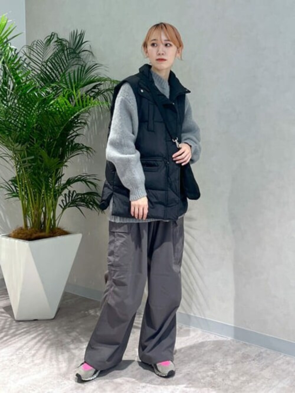 グレー系のニット/セーター、ブラック系のダウンベスト、グレー系のカーゴパンツを着用したレディースの冬コーディネートの1枚目の写真