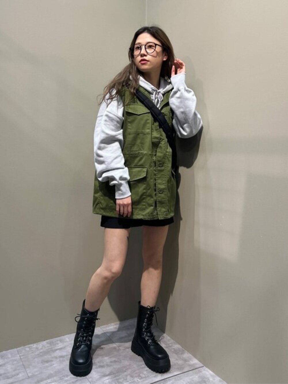 グリーン系のベスト、ブラック系のスラックス、ブラック系のブーツを着用したレディースの冬コーディネートの1枚目の写真