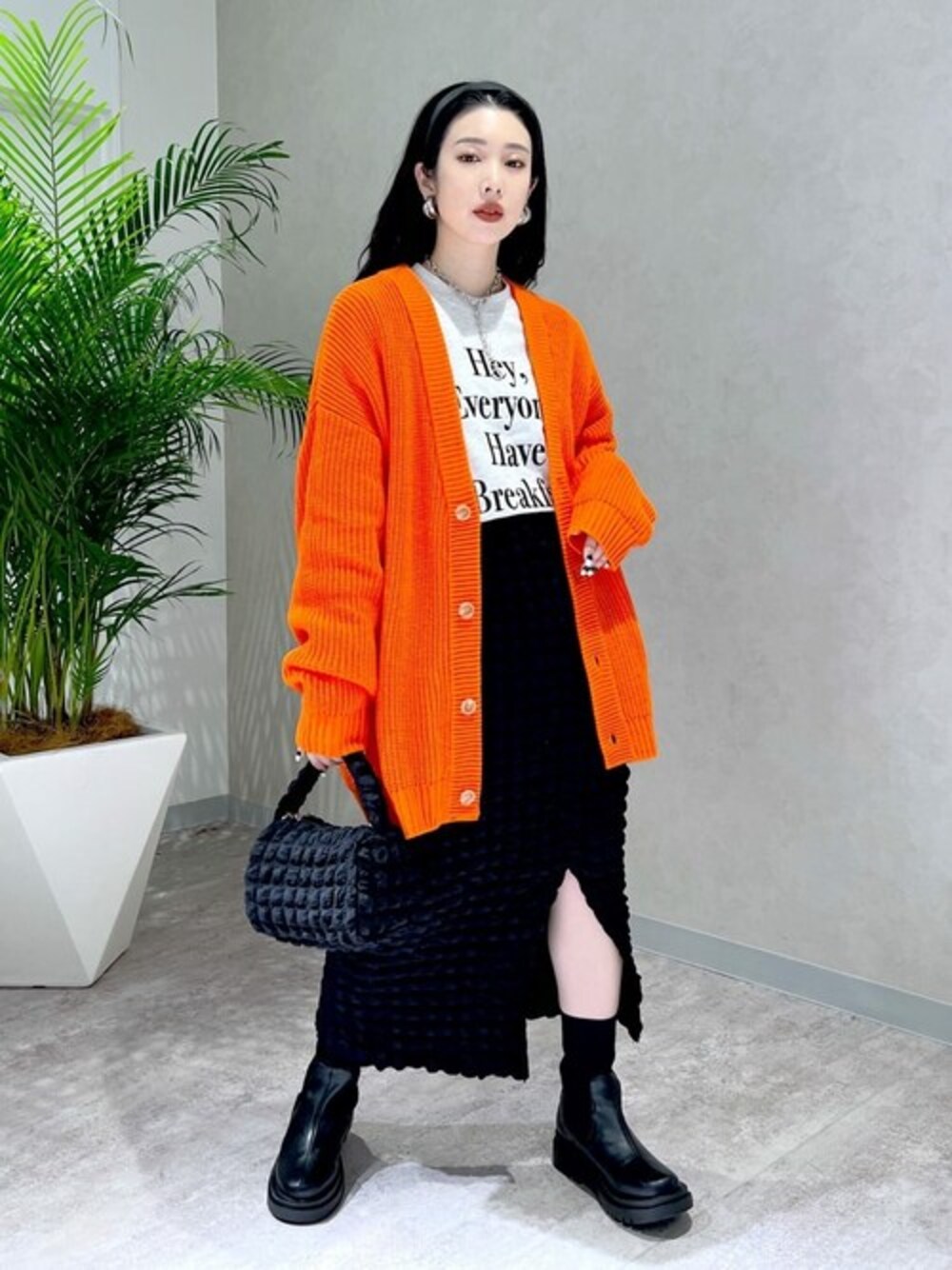 オレンジ系のカーディガン/ボレロ、ベージュ系のスウェット、ブラック系のスカートを着用したレディースの冬コーディネートの1枚目の写真