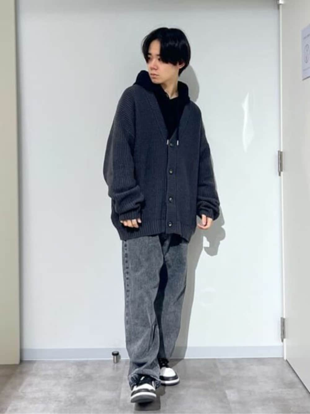 グレー系のカーディガン/ボレロ、ブラック系のパーカー、ブラック系のデニムパンツを着用したメンズの春コーディネートの1枚目の写真