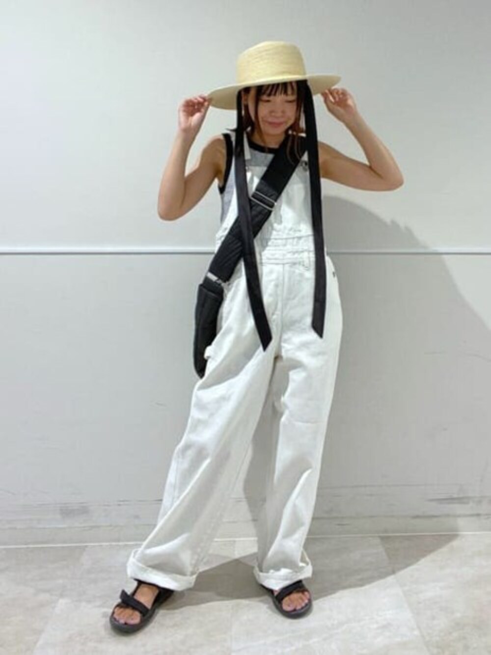 ブラック系のタンクトップ、ホワイト系のサロペット/オーバーオール、ブラック系のショルダーバッグを着用したレディースの夏コーディネートの1枚目の写真