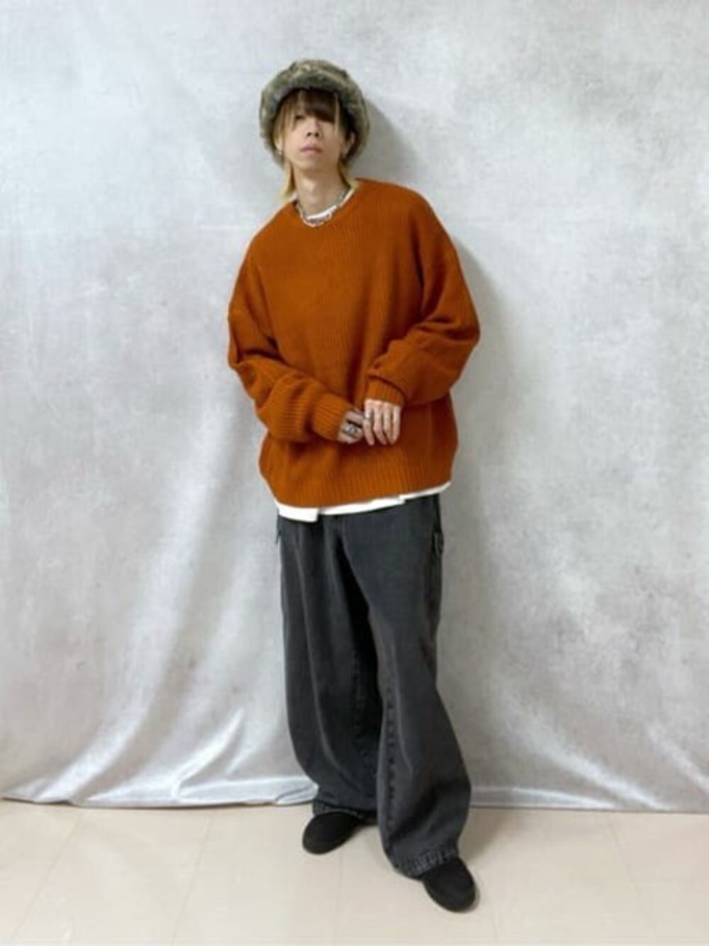 オレンジ系のニット/セーター、ホワイト系のTシャツ/カットソー、ブラック系のカーゴパンツを着用したメンズの秋コーディネートの1枚目の写真