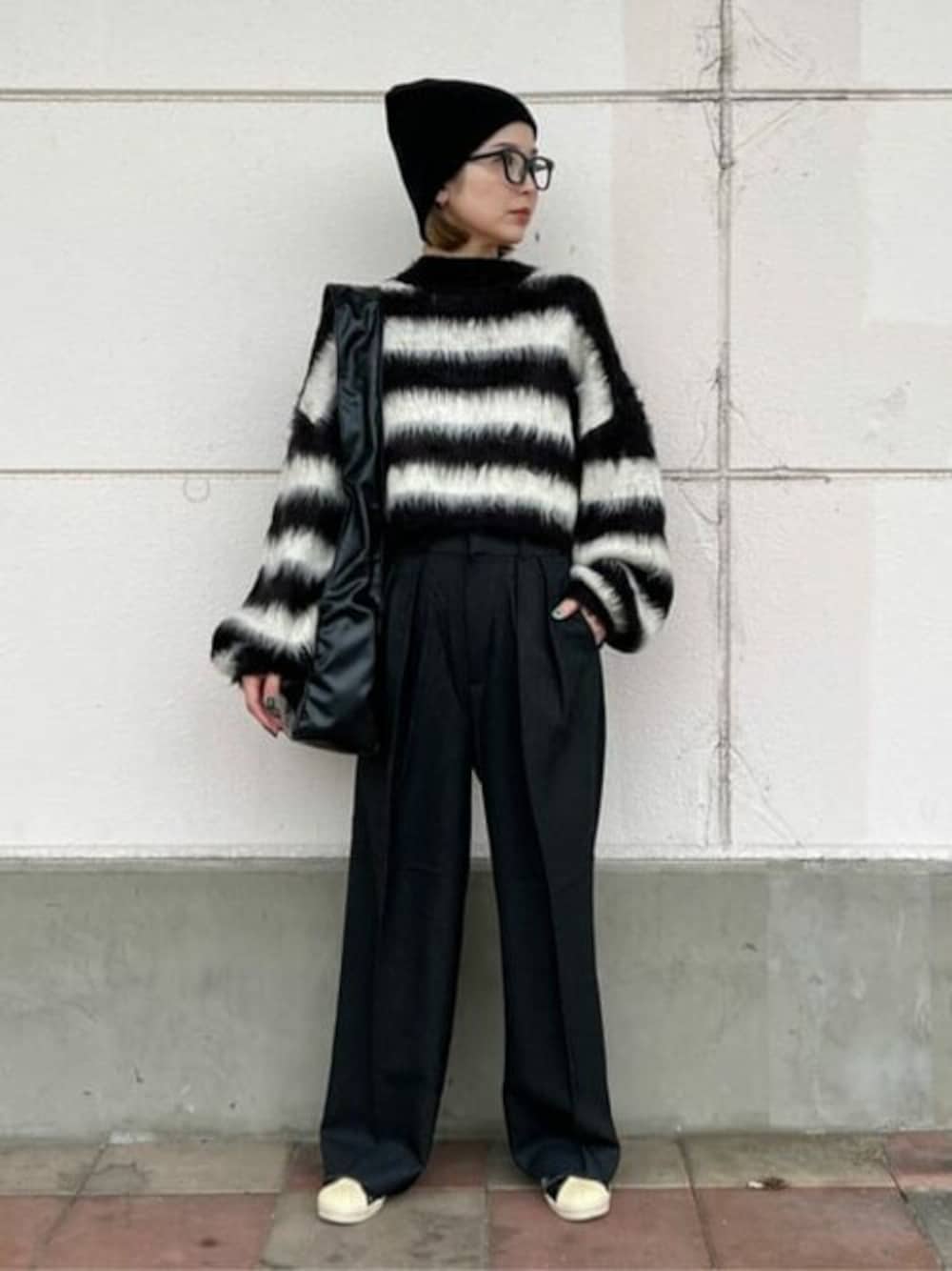 ブラック系のニット/セーター、グレー系のスラックス、ブラック系のショルダーバッグを着用したレディースの秋コーディネートの1枚目の写真