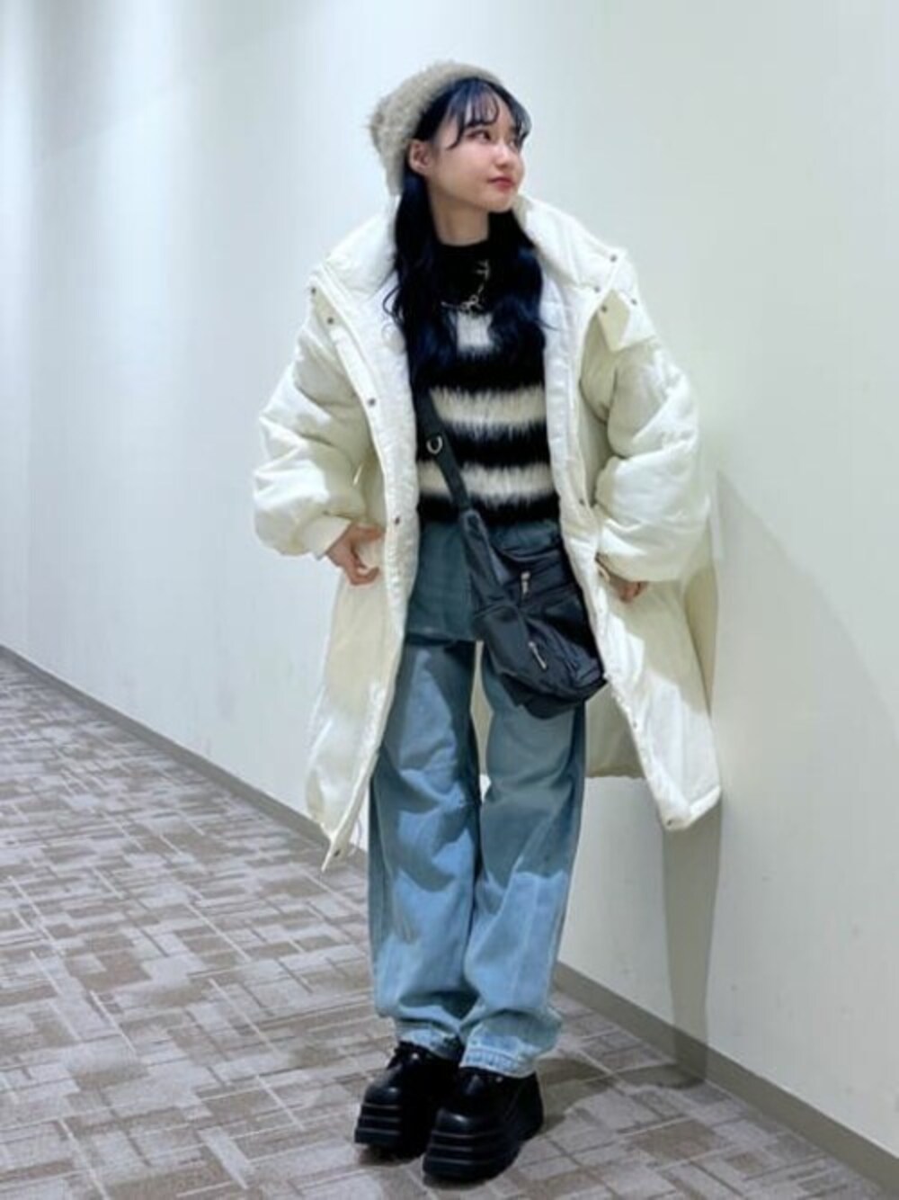 ホワイト系のダウンジャケット/コート、ブラック系のニット/セーター、ブルー系のデニムパンツを着用したレディースの秋コーディネートの1枚目の写真