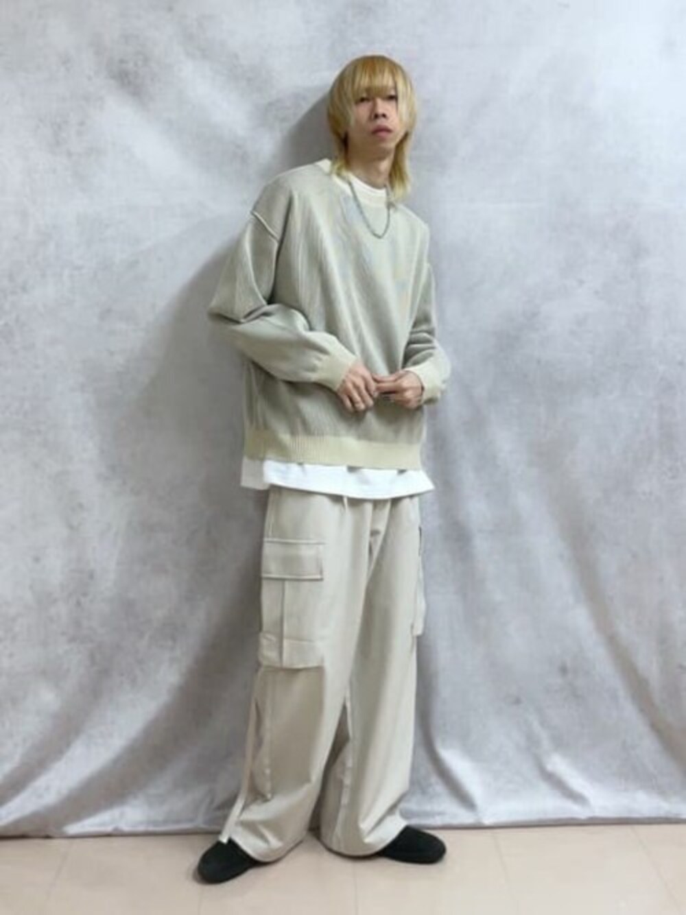 ホワイト系のニット/セーター、ベージュ系のカーゴパンツ、ホワイト系のTシャツ/カットソーを着用したメンズの春コーディネートの1枚目の写真