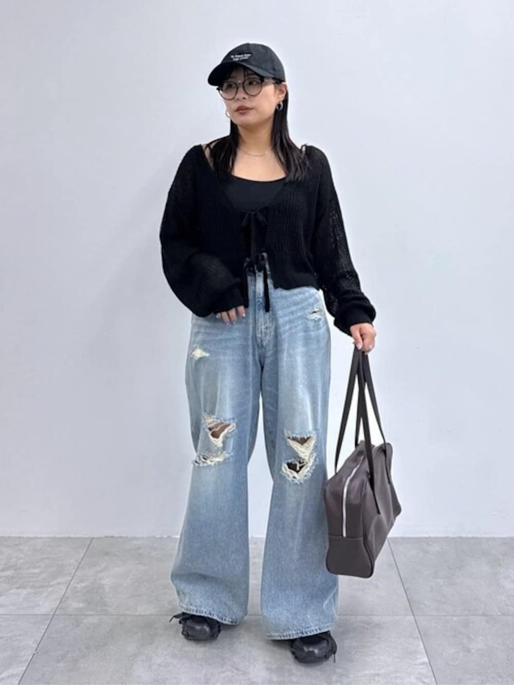 ブラック系のカーディガン/ボレロ、ブラウン系のショルダーバッグ、ブルー系のデニムパンツを着用したレディースの秋コーディネートの1枚目の写真