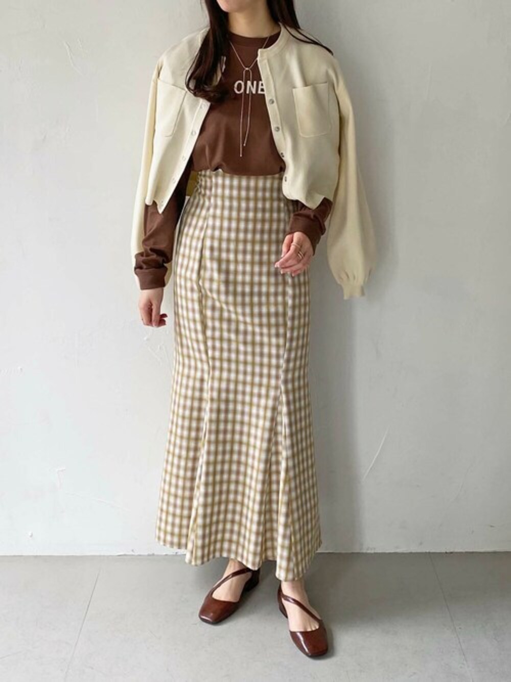 ブラウン系のTシャツ/カットソー、ホワイト系のカーディガン/ボレロ、ゴールド系のネックレスを着用したレディースの春コーディネートの1枚目の写真