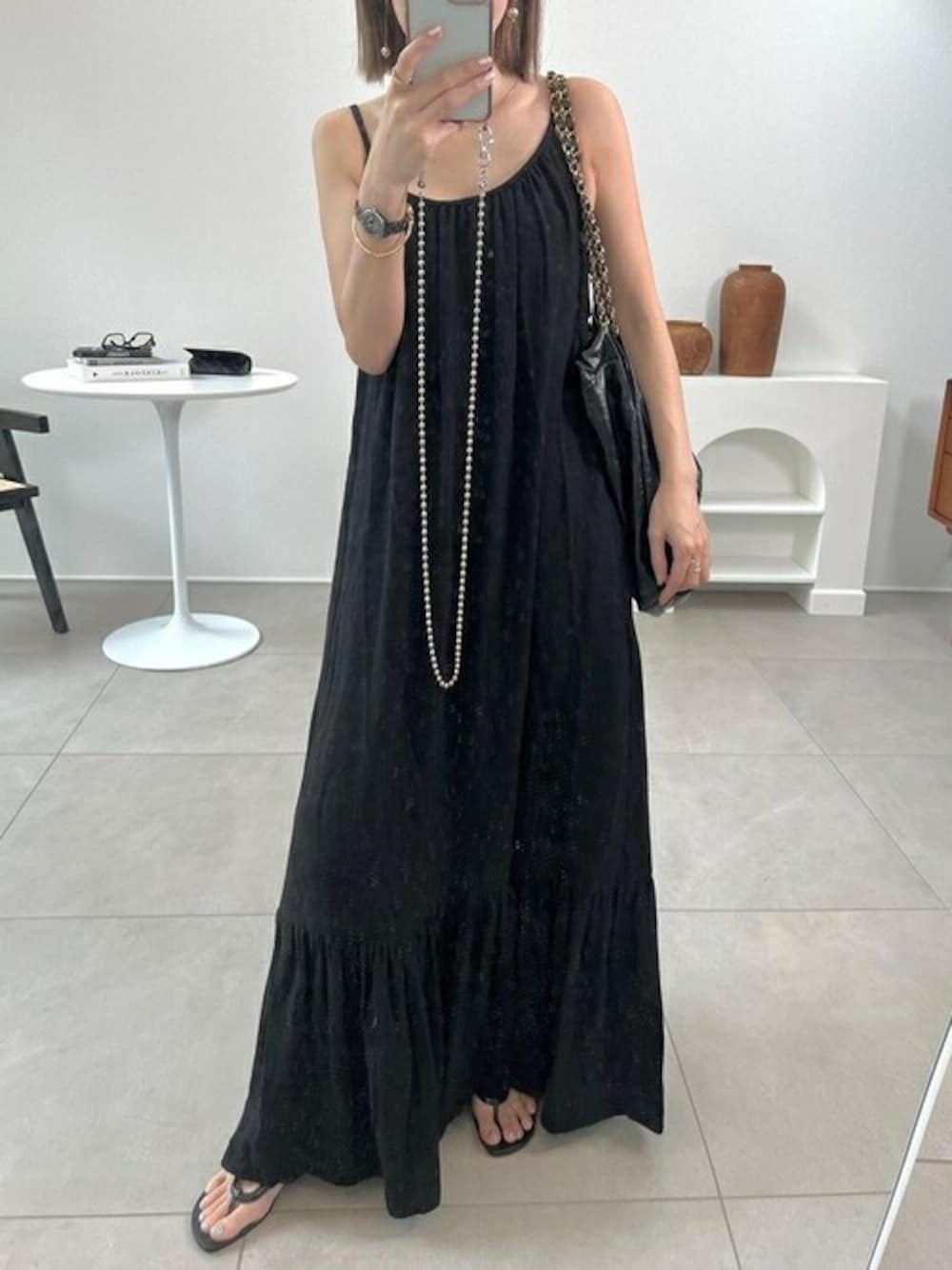 ブラック系のジャンパースカートを着用したレディースの夏コーディネートの1枚目の写真