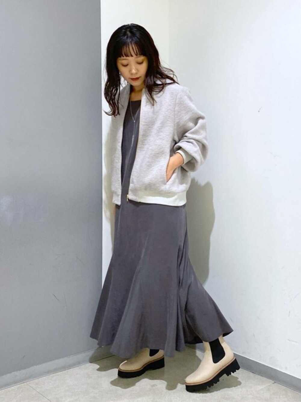 グレー系のブルゾン、グレー系のワンピース、ベージュ系のブーツを着用したレディースの秋コーディネートの1枚目の写真