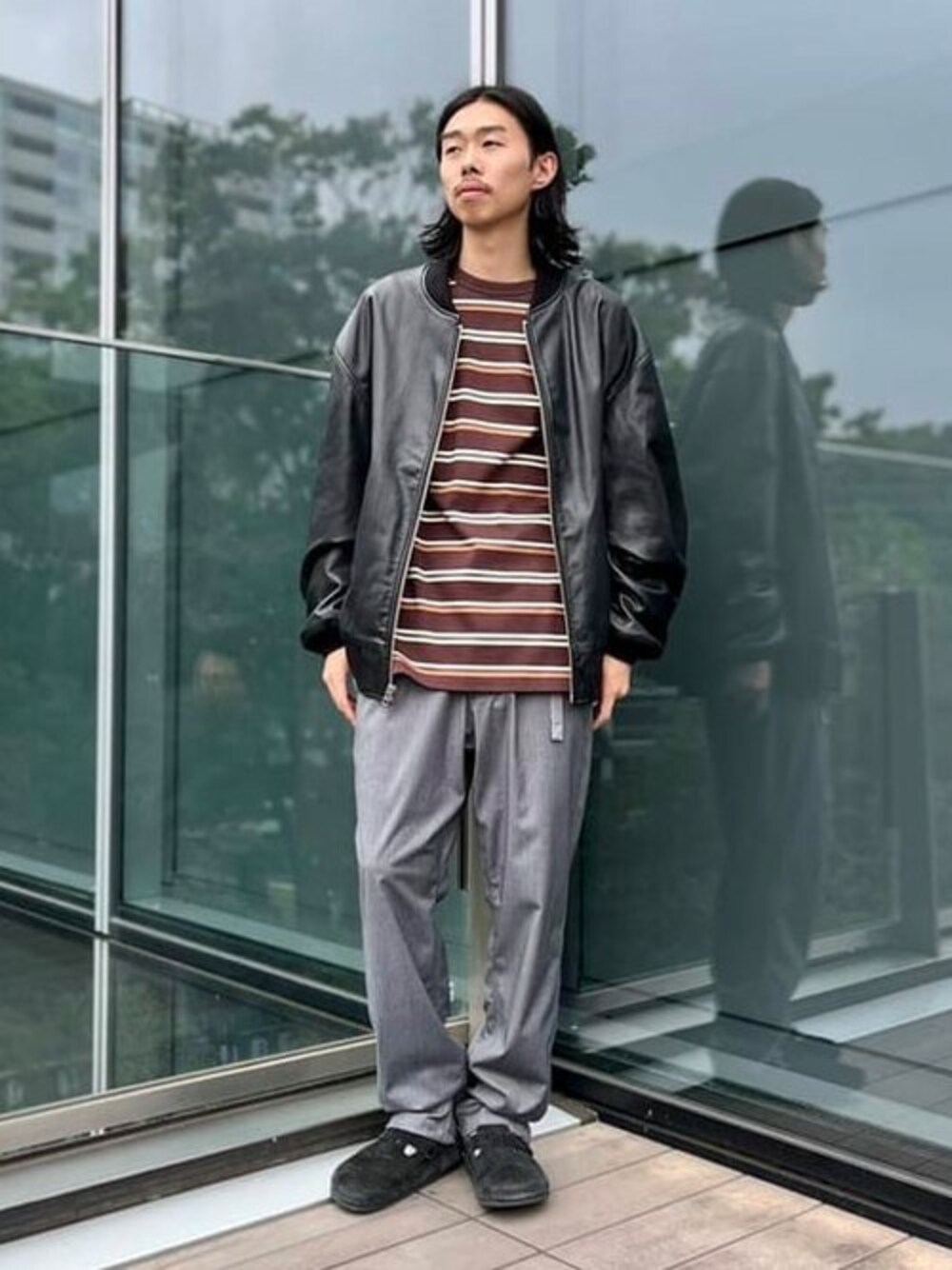 ブラック系のブルゾン、ブラウン系のTシャツ/カットソー、グレー系のスラックスを着用したメンズの夏コーディネートの1枚目の写真