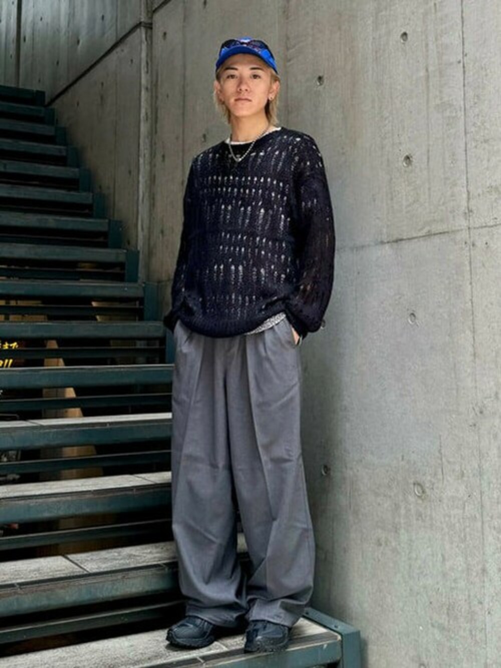 グレー系のスラックス、ブラック系のニット/セーター、ブラック系のスニーカーを着用したメンズの夏コーディネートの1枚目の写真