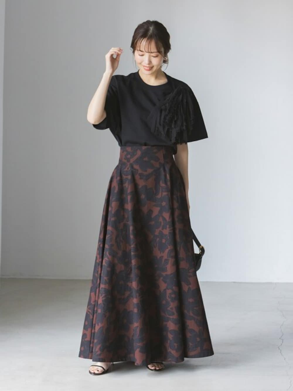 ブラック系のTシャツ/カットソー、ブラウン系のスカート、ブラック系のサンダルを着用したレディースの春コーディネートの1枚目の写真