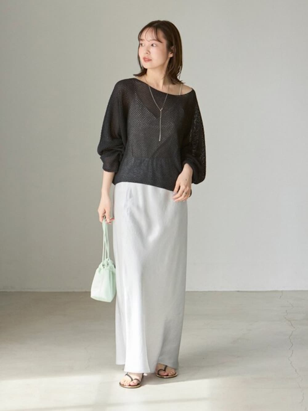 グレー系のスカート、ブラック系のニット/セーターを着用したレディースの春コーディネートの1枚目の写真