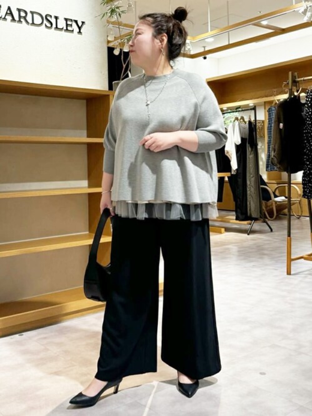 ブラック系のスラックス、グレー系のニット/セーター、シルバー系のネックレスを着用したレディースの夏コーディネートの1枚目の写真