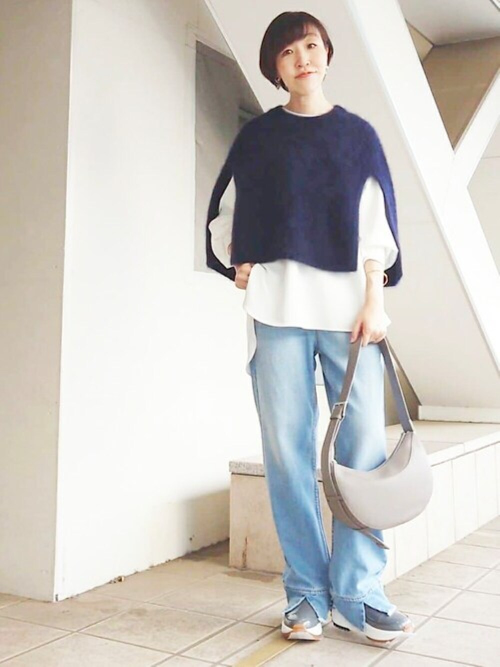 ブルー系のニット/セーター、ホワイト系のTシャツ/カットソー、ブルー系のデニムパンツを着用したレディースの秋コーディネートの1枚目の写真