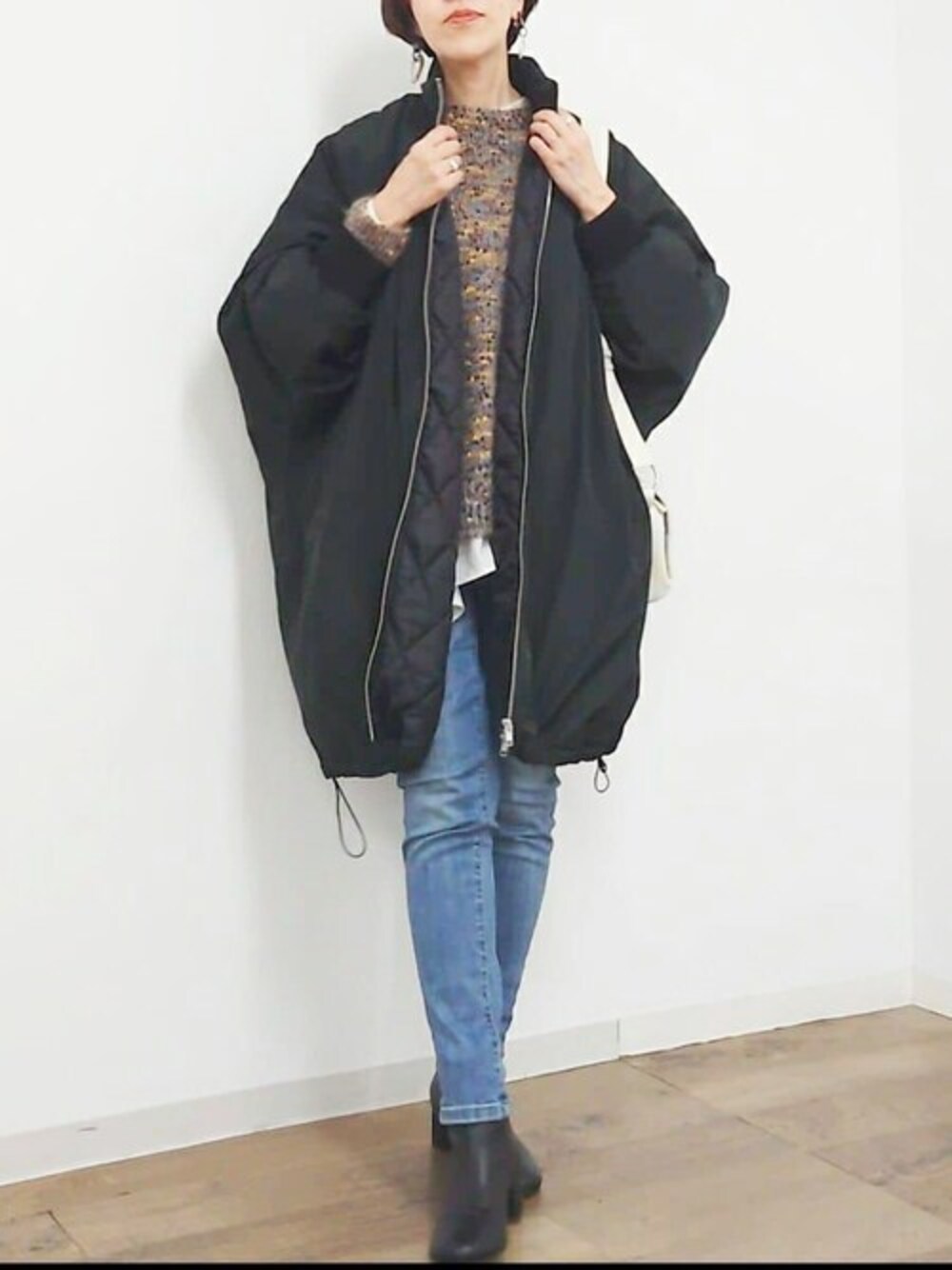 ブラック系のその他アウター、イエロー系のニット/セーター、ブルー系のデニムパンツを着用したレディースの秋コーディネートの1枚目の写真