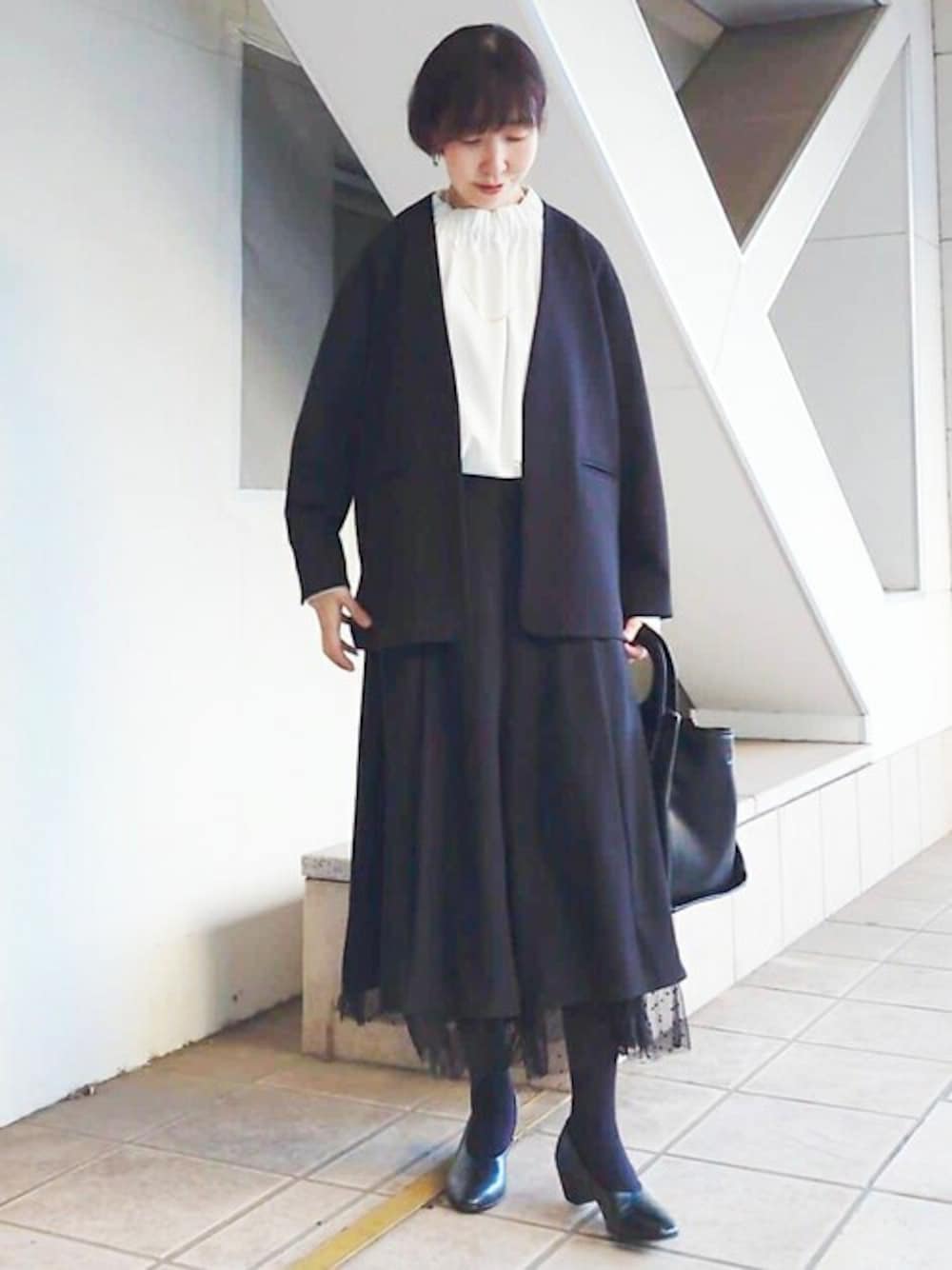 ブラック系のノーカラージャケット、ホワイト系のシャツ/ブラウス、ブラック系のトートバッグを着用したレディースの秋コーディネートの1枚目の写真