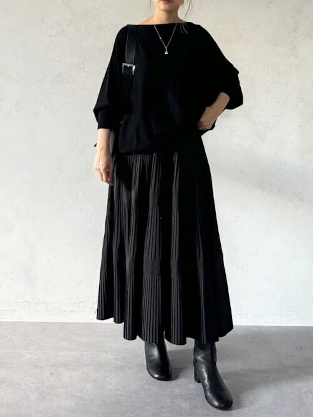 ブラック系のニット/セーター、ブラック系のスカート、ブラック系のショルダーバッグを着用したレディースの秋コーディネートの1枚目の写真