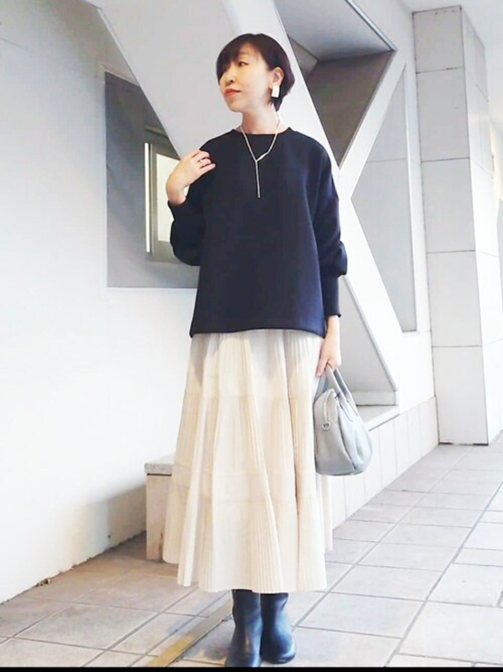 ブラック系のTシャツ/カットソー、ホワイト系のスカート、グレー系のショルダーバッグを着用したレディースの冬コーディネートの1枚目の写真