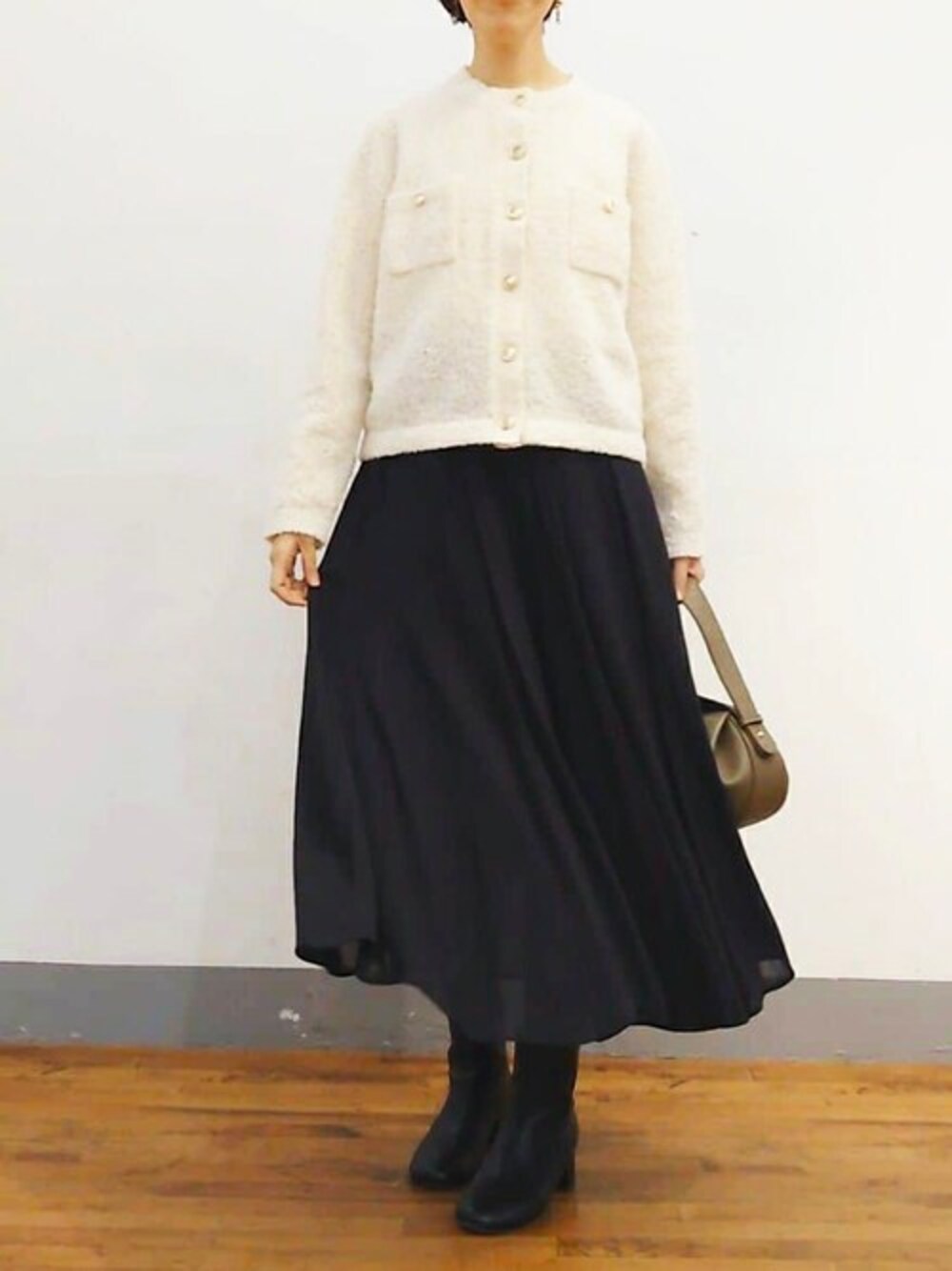 ブラック系のスカート、ブラウン系のショルダーバッグ、ブラック系のブーツを着用したレディースの冬コーディネートの1枚目の写真