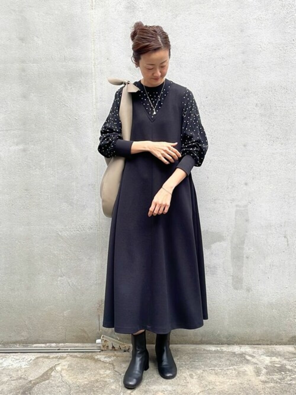 グレー系のトートバッグ、ブラック系のワンピースを着用したレディースの冬コーディネートの1枚目の写真