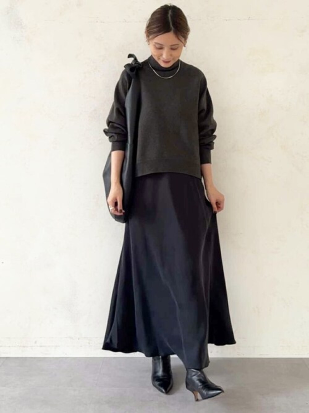 グレー系のニット/セーター、ブラック系のスカート、ブラック系のトートバッグを着用したレディースの冬コーディネートの1枚目の写真