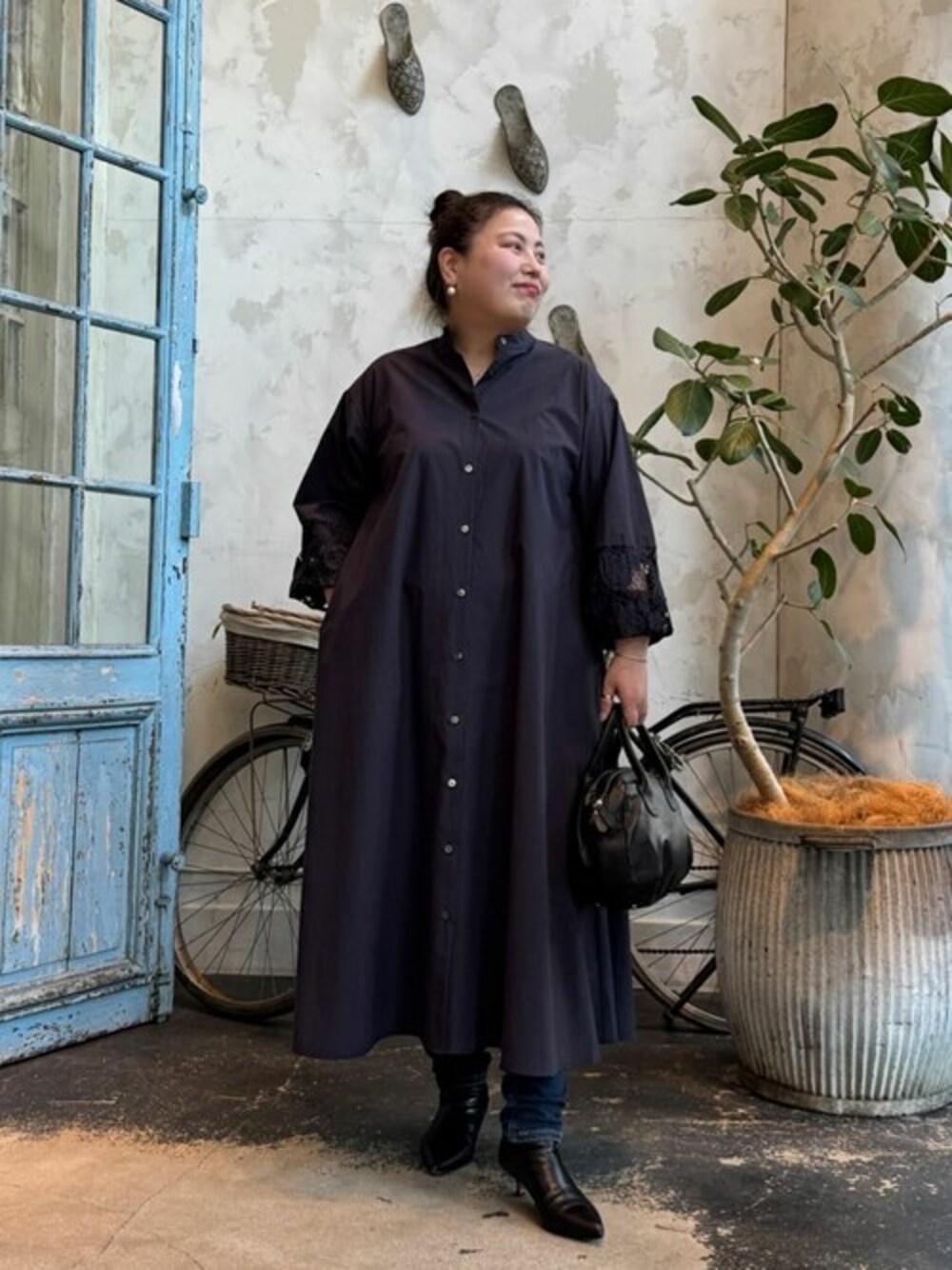 ブルー系のワンピース、ブラック系のショルダーバッグ、ブルー系のデニムパンツを着用したレディースの冬コーディネートの1枚目の写真