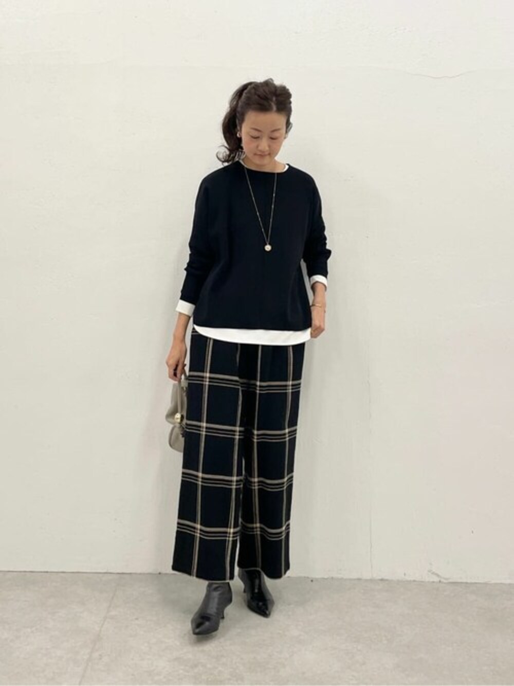 ブラック系のニット/セーター、ブラック系のその他パンツ、ホワイト系のTシャツ/カットソーを着用したレディースの冬コーディネートの1枚目の写真