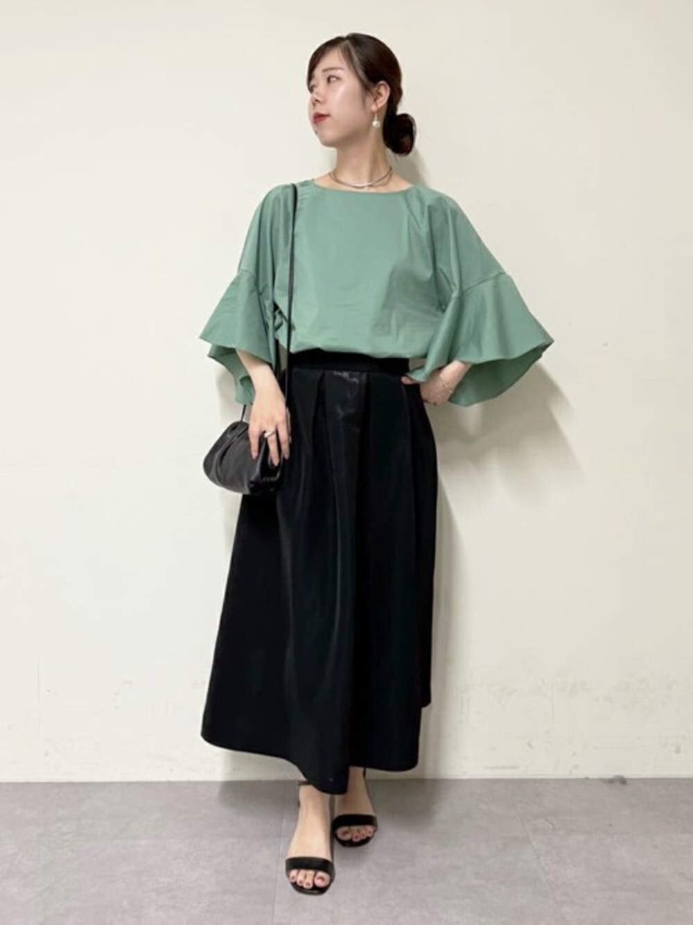 グリーン系のシャツ/ブラウス、ブラック系のスカート、ブラック系のトートバッグを着用したレディースの春コーディネートの1枚目の写真