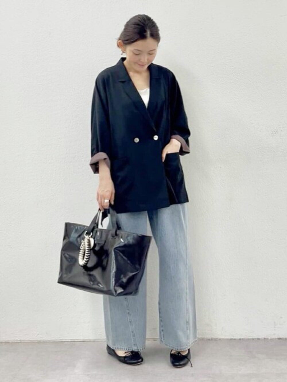 ブラック系のテーラードジャケット、ホワイト系のタンクトップ、ブルー系のデニムパンツを着用したレディースの春コーディネートの1枚目の写真