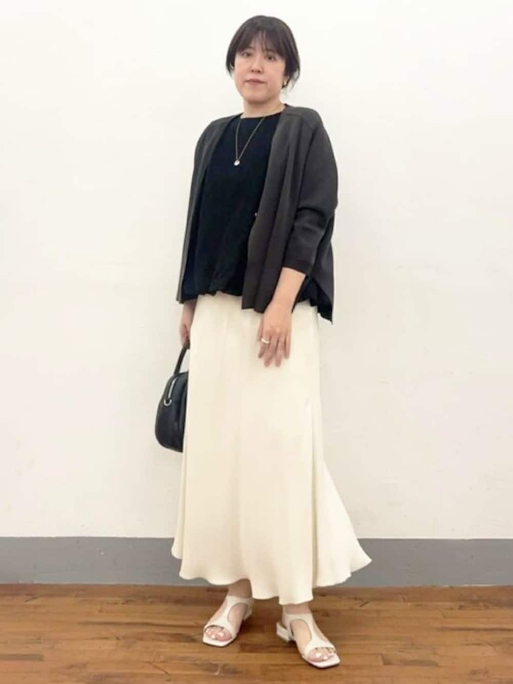 グレー系のカーディガン/ボレロ、ブラック系のシャツ/ブラウス、ホワイト系のスカートを着用したレディースの春コーディネートの1枚目の写真