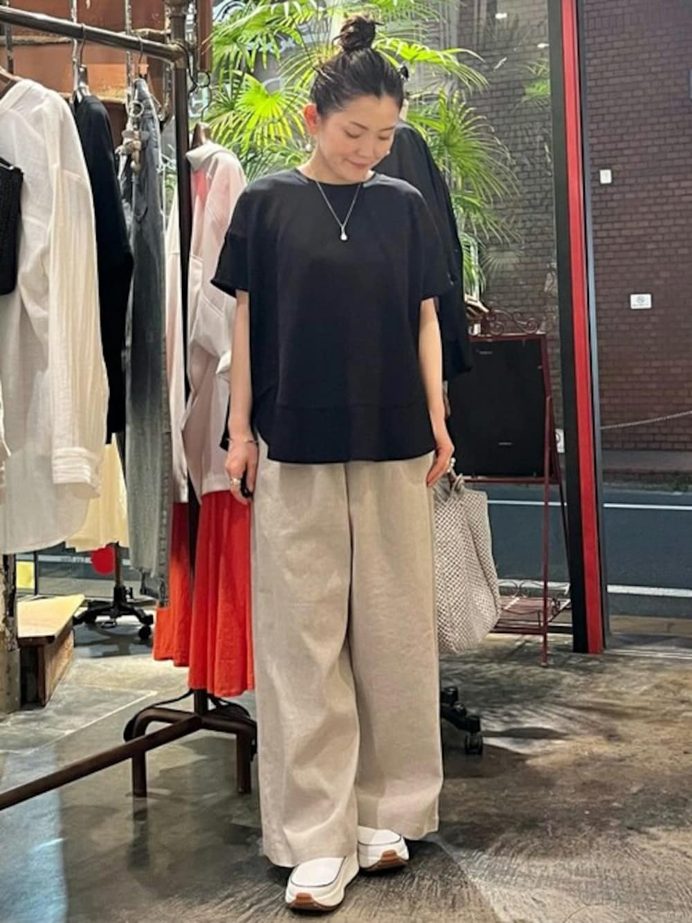 ブラック系のTシャツ/カットソー、ベージュ系のその他パンツ、ホワイト系のポーチを着用したレディースの春コーディネートの1枚目の写真