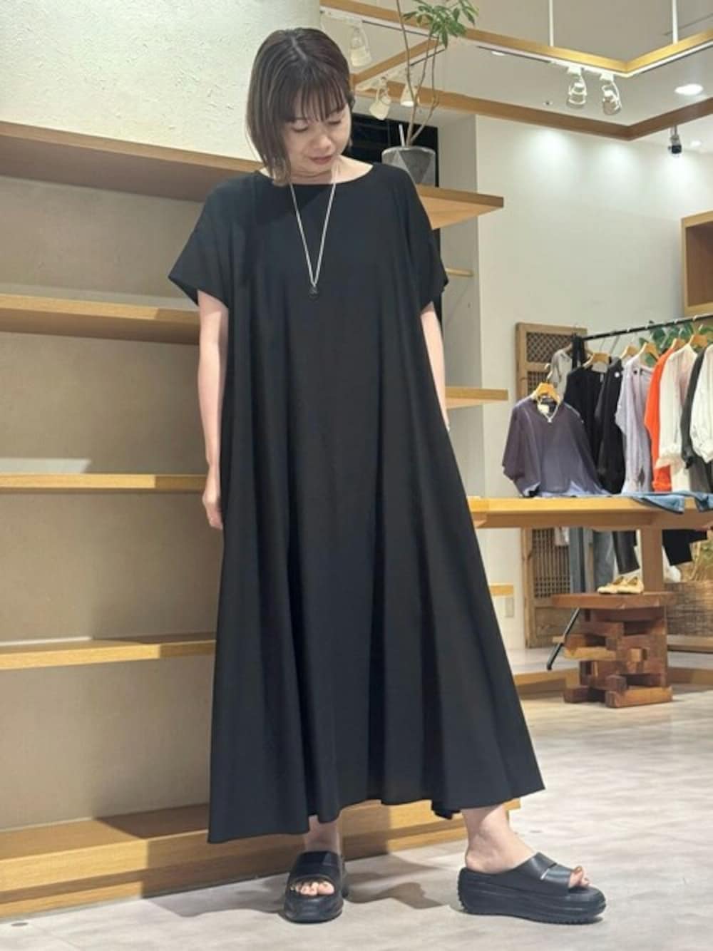 ブラック系のワンピース、ブラック系のサンダル、シルバー系のピアス(両耳用)を着用したレディースの春コーディネートの1枚目の写真