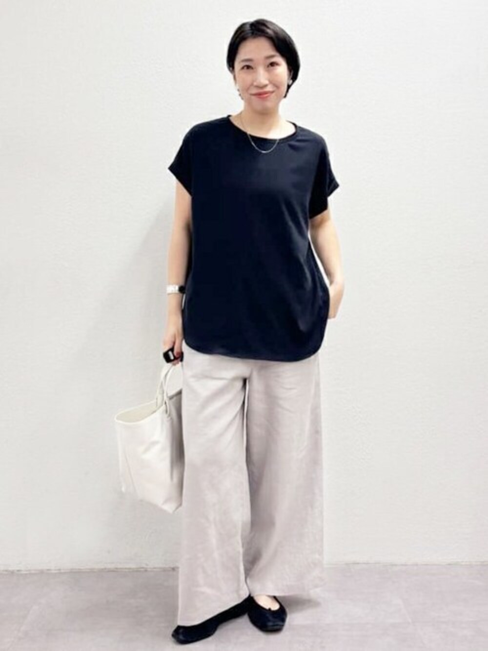 ブラック系のシャツ/ブラウス、グレー系のその他パンツ、ホワイト系のトートバッグを着用したレディースの春コーディネートの1枚目の写真