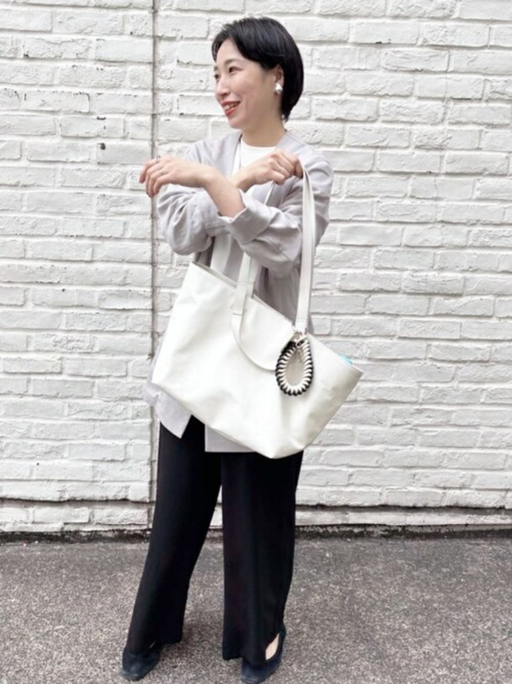 グレー系のブルゾン、ホワイト系のTシャツ/カットソー、ブラック系のその他パンツを着用したレディースの春コーディネートの1枚目の写真