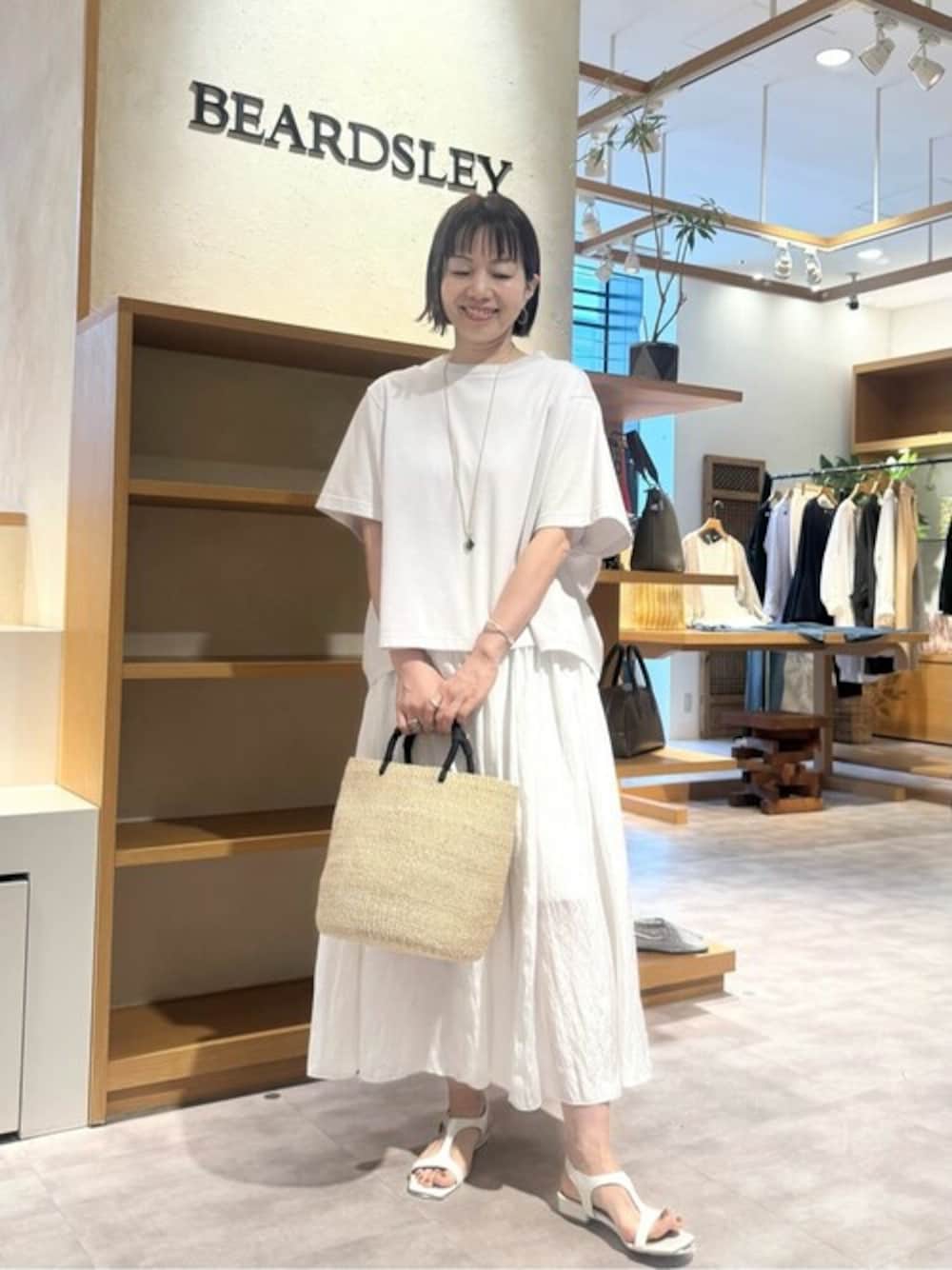 グレー系のTシャツ/カットソー、ホワイト系のスカート、ベージュ系のかごバッグを着用したレディースの春コーディネートの1枚目の写真