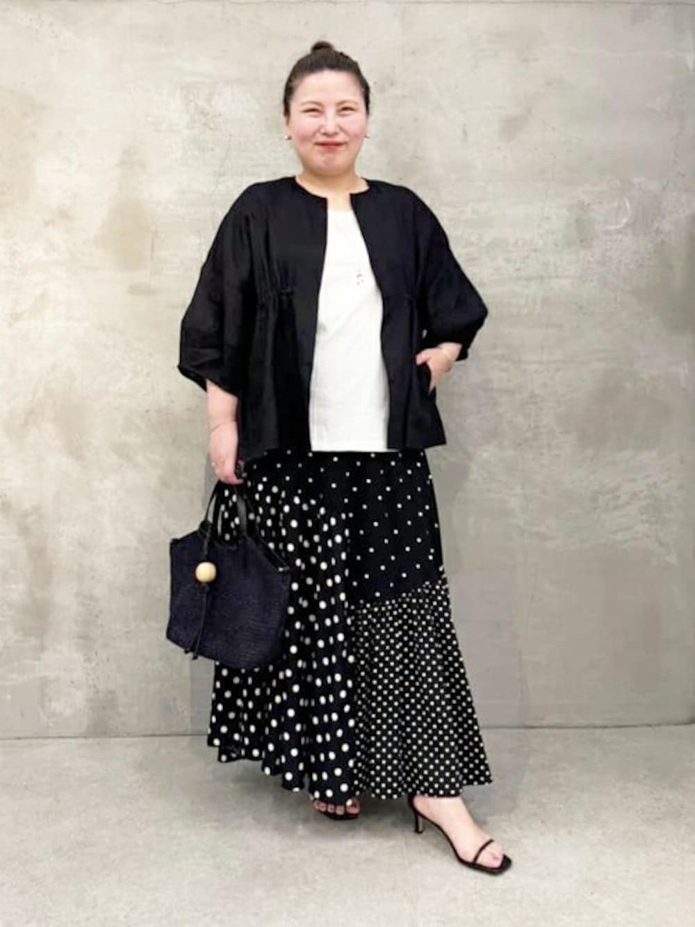 ブラック系のスカート、ブラック系のブルゾン、ホワイト系のタンクトップを着用したレディースの夏コーディネートの1枚目の写真