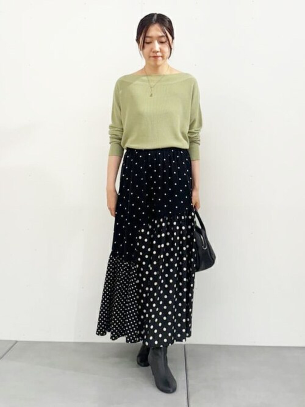 グリーン系のニット/セーター、ブラック系のスカートを着用したレディースの夏コーディネートの1枚目の写真