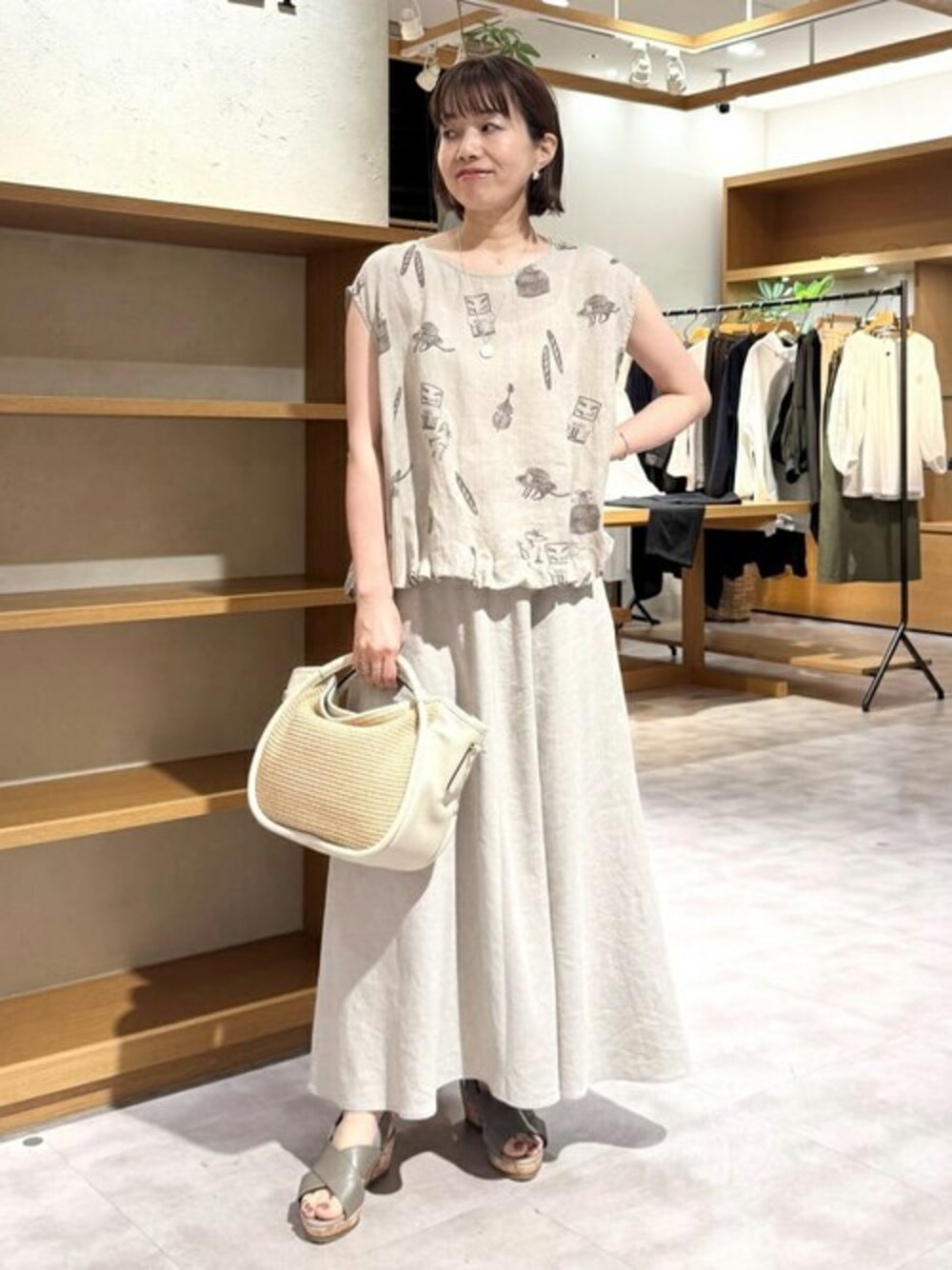 ベージュ系のシャツ/ブラウス、ベージュ系のスカート、ホワイト系のトートバッグを着用したレディースの夏コーディネートの1枚目の写真
