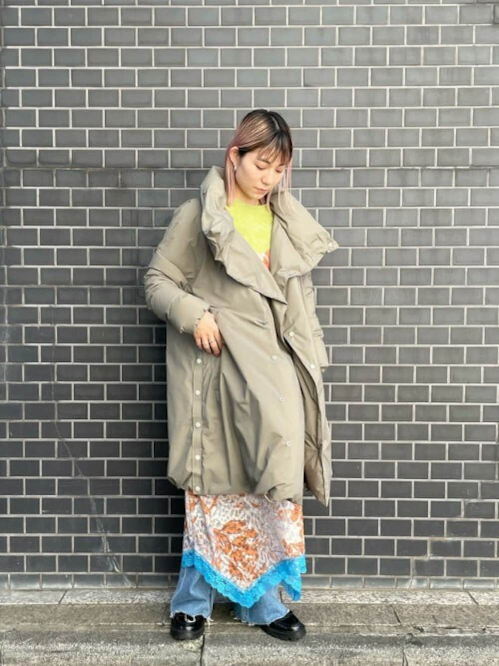 グリーン系のダウンジャケット/コート、ブルー系のデニムパンツ、ベージュ系のワンピースを着用したレディースの冬コーディネートの1枚目の写真