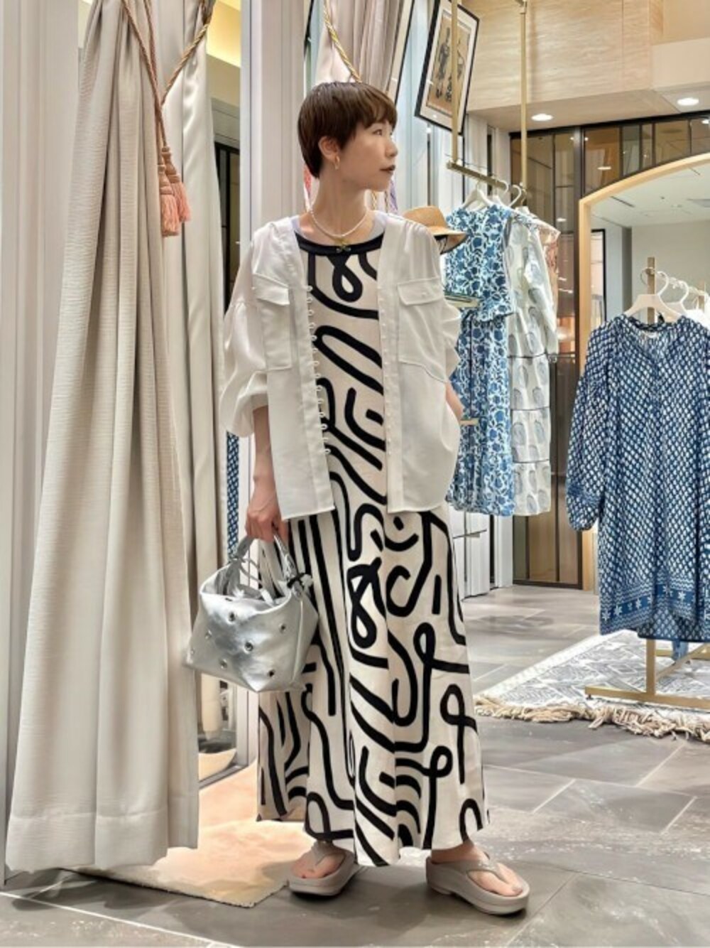 ベージュ系のワンピース、パープル系のタンクトップ、ベージュ系のサンダルを着用したレディースの春コーディネートの1枚目の写真