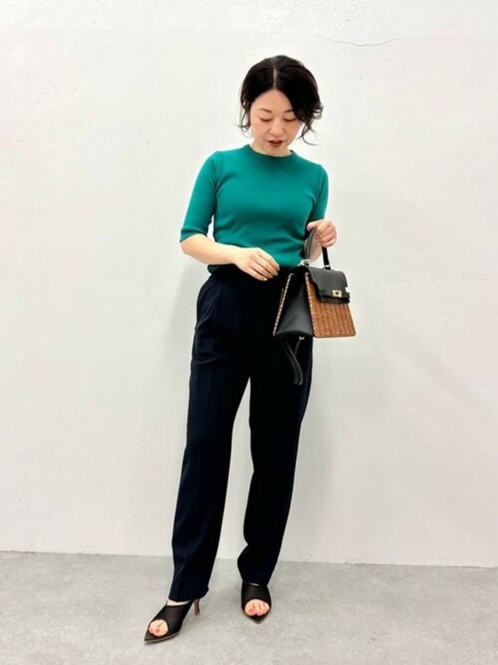 グリーン系のTシャツ/カットソー、ブルー系のスラックス、ブラック系のかごバッグを着用したレディースの春コーディネートの1枚目の写真