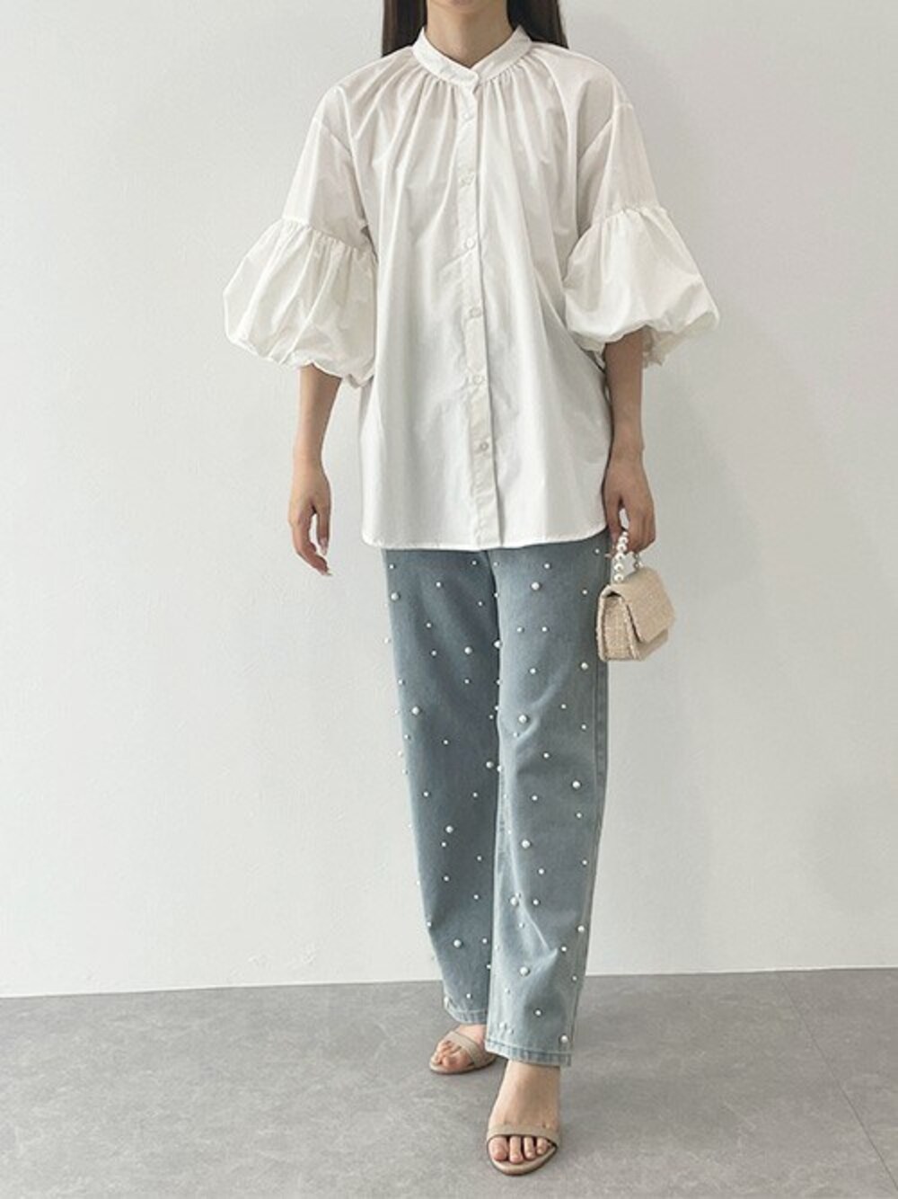 ベージュ系のハンドバッグ、ホワイト系のシャツ/ブラウス、ブルー系のデニムパンツを着用したレディースの夏コーディネートの1枚目の写真