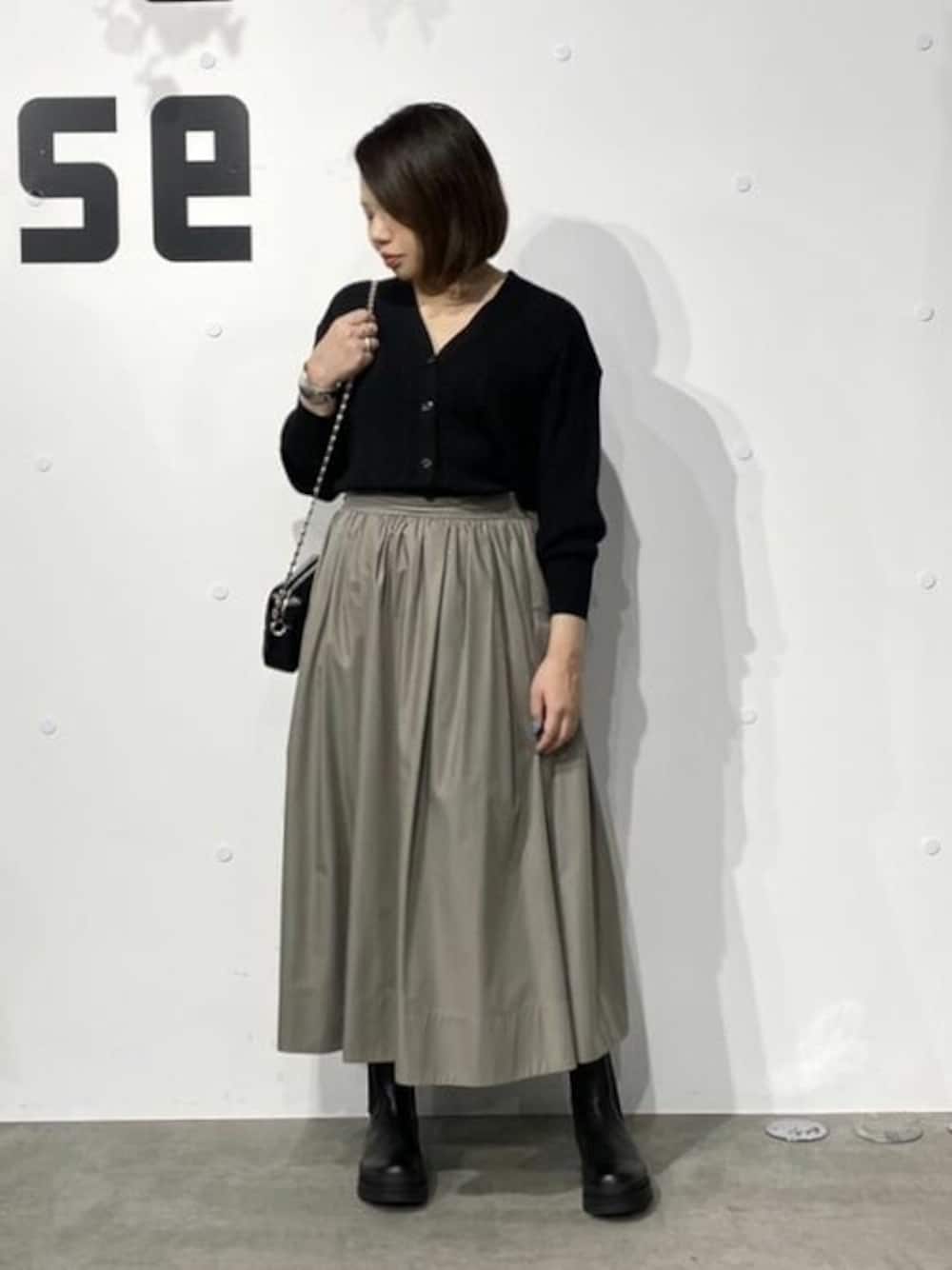 ブラック系のニット/セーター、グリーン系のスカート、ブラック系のショルダーバッグを着用したレディースの秋コーディネートの1枚目の写真