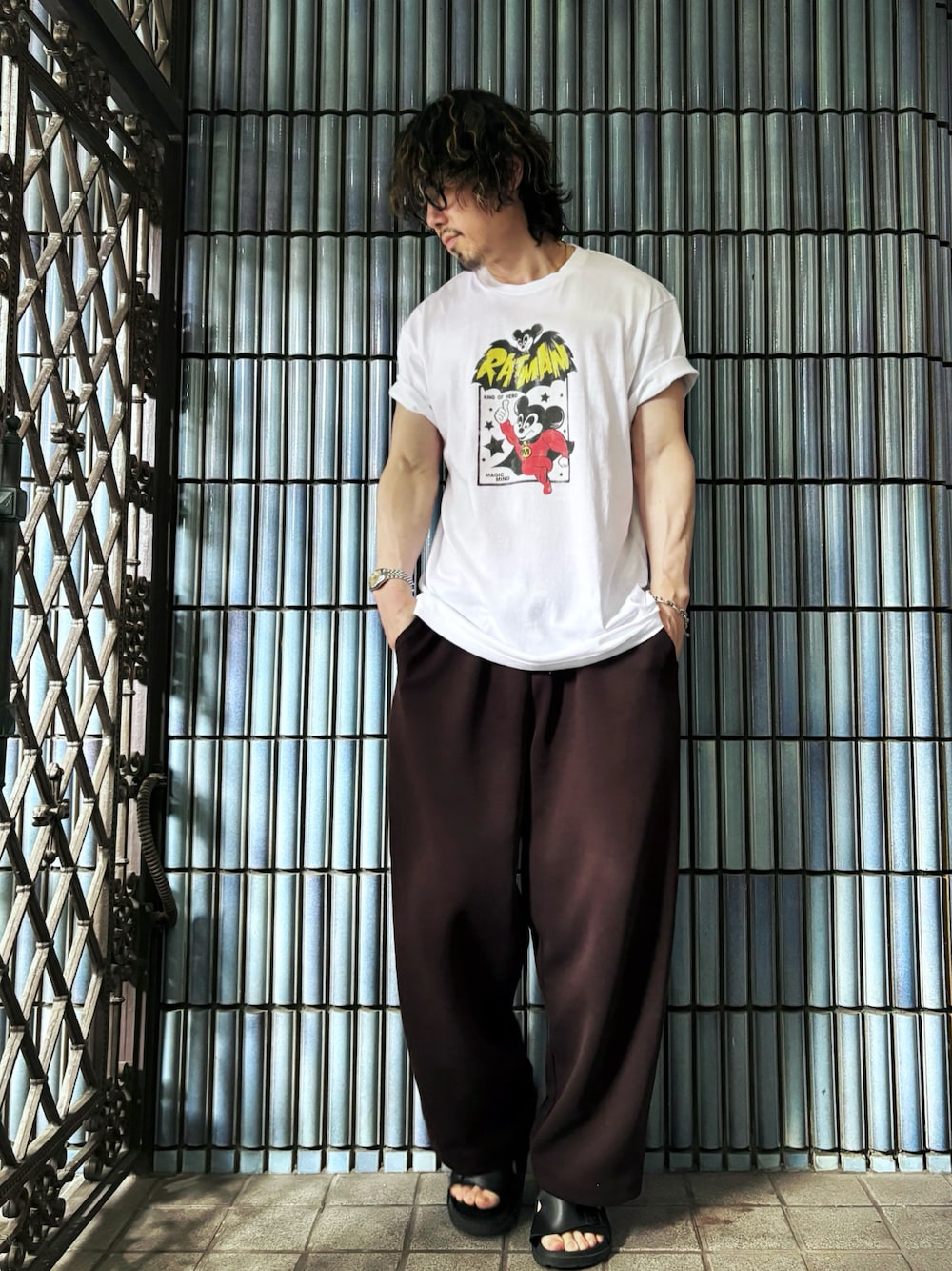 ブラック系のサンダル、ホワイト系のTシャツ/カットソー、ブラウン系のスウェットパンツを着用したメンズの夏コーディネートの1枚目の写真