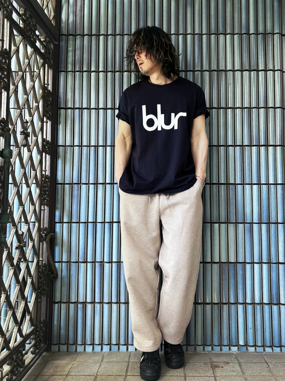 ブラック系のスニーカー、ブルー系のTシャツ/カットソー、ベージュ系のスウェットパンツを着用したメンズの春コーディネートの1枚目の写真