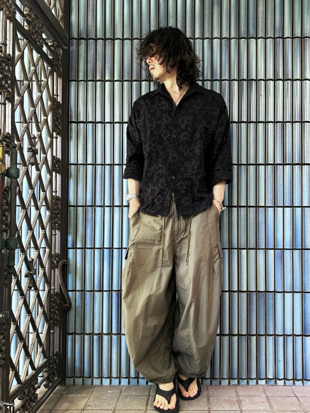 グリーン系のカーゴパンツ、ブラック系のサンダル、ブラック系のシャツ/ブラウスを着用したメンズの夏コーディネートの1枚目の写真