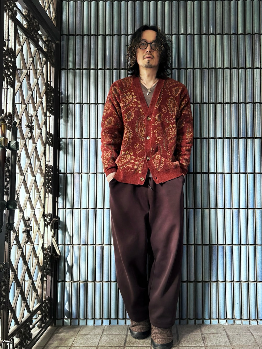 レッド系のカーディガン/ボレロ、ブラウン系のニット/セーター、ブラウン系のスウェットパンツを着用したメンズの冬コーディネートの1枚目の写真