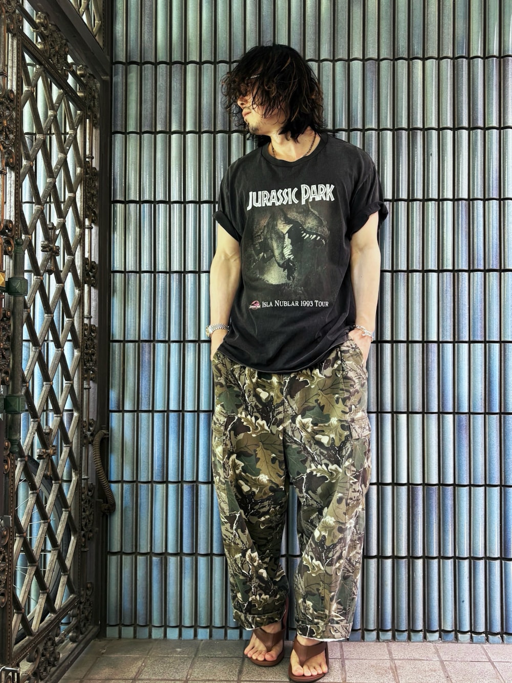 ブラウン系のサンダル、グリーン系のカーゴパンツ、ブラック系のTシャツ/カットソーを着用したメンズの夏コーディネートの1枚目の写真